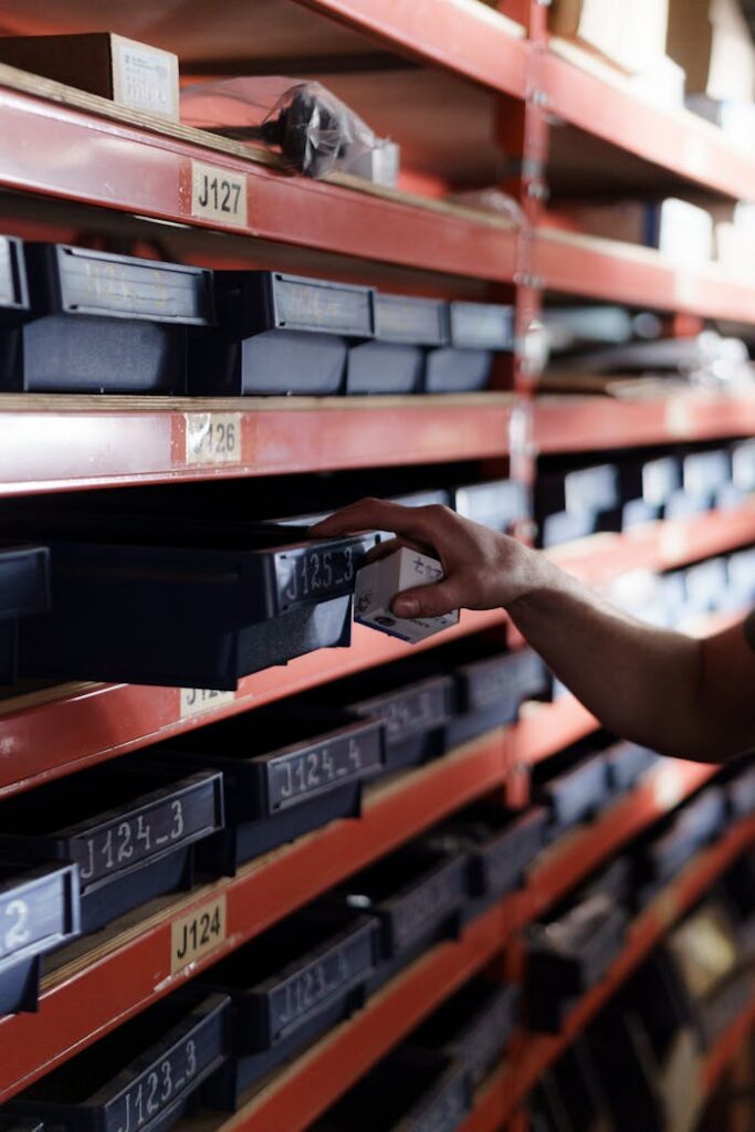 Hand reaching for storage bin in organized warehouse shelving. Perfect for logistics and inventory themes.