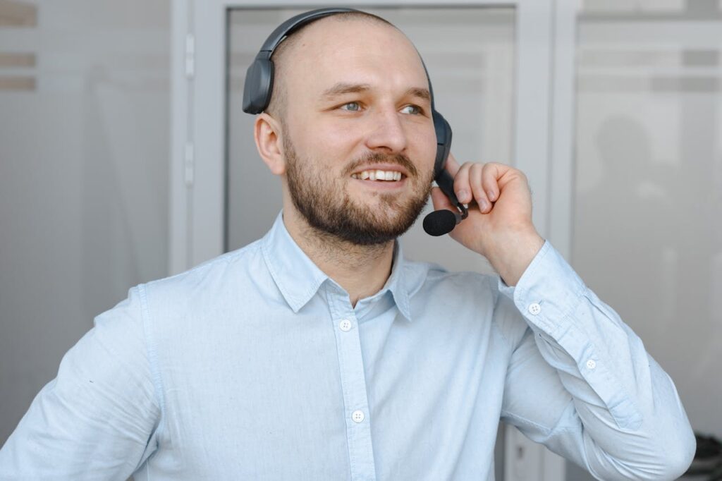 Smiling call center agent wearing a headset providing customer service in an office environment.